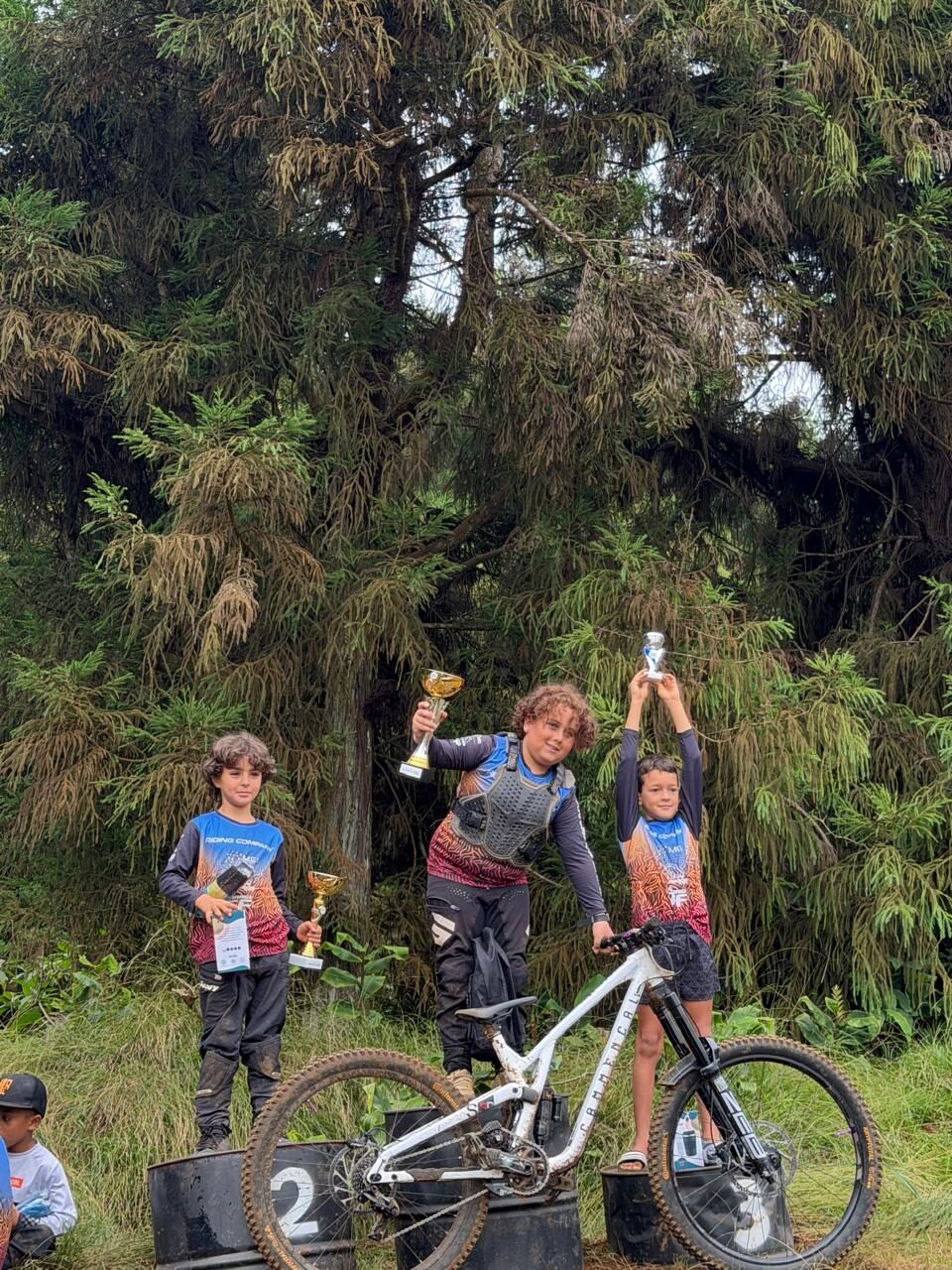 Trois jeunes riders sur un podium avec leurs trophées
